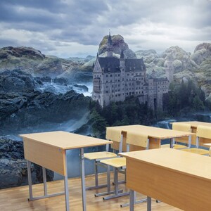 May include: A classroom with a large mural of a castle on a rocky cliff with a waterfall. The mural is behind several wooden desks and chairs.