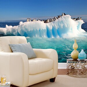 May include: A group of penguins perched on a large, blue iceberg floating in a turquoise ocean. The iceberg is partially submerged in the water, creating a dramatic scene.