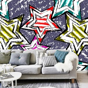 May include: A grey sofa with colourful cushions in front of a wall with a graphic pattern of overlapping stars in red, yellow, green, blue, and pink. The stars have a striped pattern.
