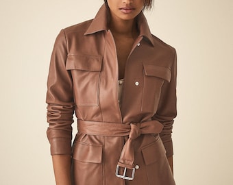 May include: A brown leather jacket with a belted waist and multiple pockets. The jacket has a button-up front and a collar.