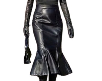 May include: A black outfit featuring a sleeveless top, a high-waisted leather skirt with a flared hem, and knee-high boots. The ensemble includes long leather gloves and a small black handbag. The outfit is all black.