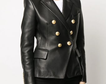 Pode incluir: Um blazer de couro preto com fecho de dupla abotoadura e detalhes de botões dourados.