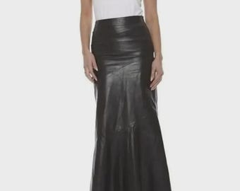 May include: A black, full-length leather skirt with a flared hem. The skirt is paired with a white tank top. The skirt appears to be made of a smooth, supple leather material.