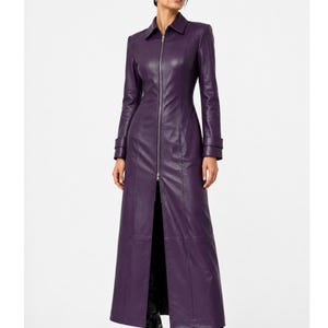 May include: A long, deep purple coat featuring a full-length silver front zipper, a classic collar, and long sleeves with cuff details. The garment is fitted through the torso and extends to the ankles, showcasing a smooth, structured finish.