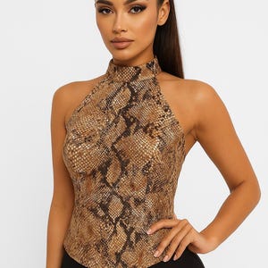 Peut inclure: Haut sans manches à motif peau de serpent dans les tons marron et beige. Le haut a un col montant et est associé à un pantalon noir. L'ensemble dégage une allure élégante et tendance.