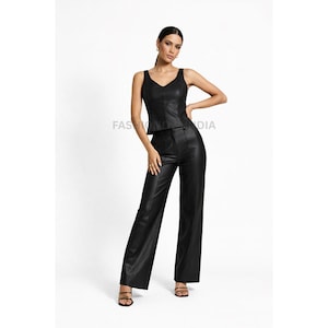May include: A black faux leather two-piece outfit. The set includes a sleeveless top with a V-neck and high-waisted, wide-leg pants. The outfit is worn with strappy sandals. The text "FASHION INDIA" is visible on the image.