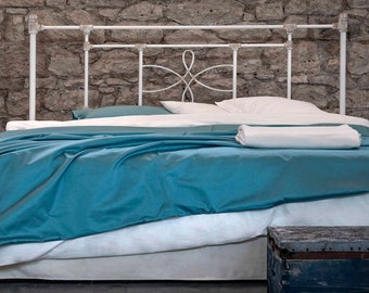 May include: White metal bed frame with a decorative headboard and a teal blue duvet cover. The bed is made with white sheets and pillows.