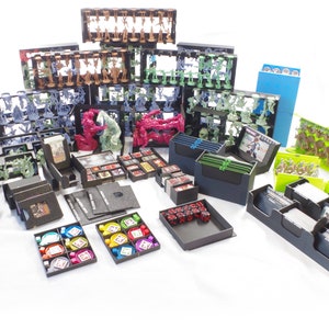 Puede incluir: Un conjunto de organizadores de plástico negro para los componentes de los juegos de mesa. Los organizadores incluyen bandejas para dados, cartas y figuras en miniatura. Las bandejas están apiladas unas sobre otras y están dispuestas en forma de pirámide. Los organizadores están diseñados para ayudar a los jugadores a mantener sus componentes de juego organizados y fáciles de acceder.