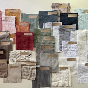 May include: A collection of 24 fabric swatches in various colors and patterns, including brown plaid, mustard, light blue, and gray. Each swatch has a handwritten label with the fabric name.