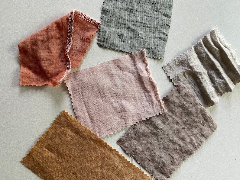 May include: Six fabric swatches in various shades of brown, pink, and orange. The swatches are all made of a natural linen fabric.