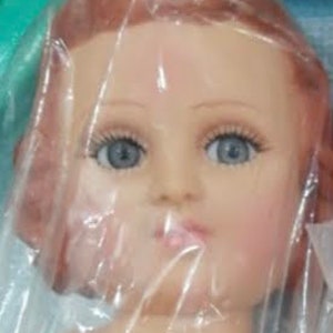 May include: A close-up of a doll head with long, straight, auburn hair. The doll has blue eyes and a painted, realistic face.