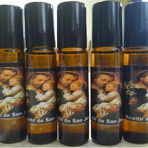 May include: Five amber glass roll-on bottles with black caps. Each bottle has a label with a picture of Saint Joseph holding a baby Jesus. The labels read "Aceite de San Jose".