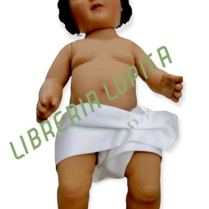 May include: A small, white-clothed doll with dark hair and a painted face. The doll is standing with its legs slightly apart and its arms outstretched.