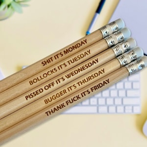 May include: Set of five wooden pencils with funny sayings about each day of the week. The pencils are engraved with the text: "Shit it's Monday", "Bollocks it's Tuesday", "Pissed off it's Wednesday", "Bugger it's Thursday", and "Thank fuck it's Friday".