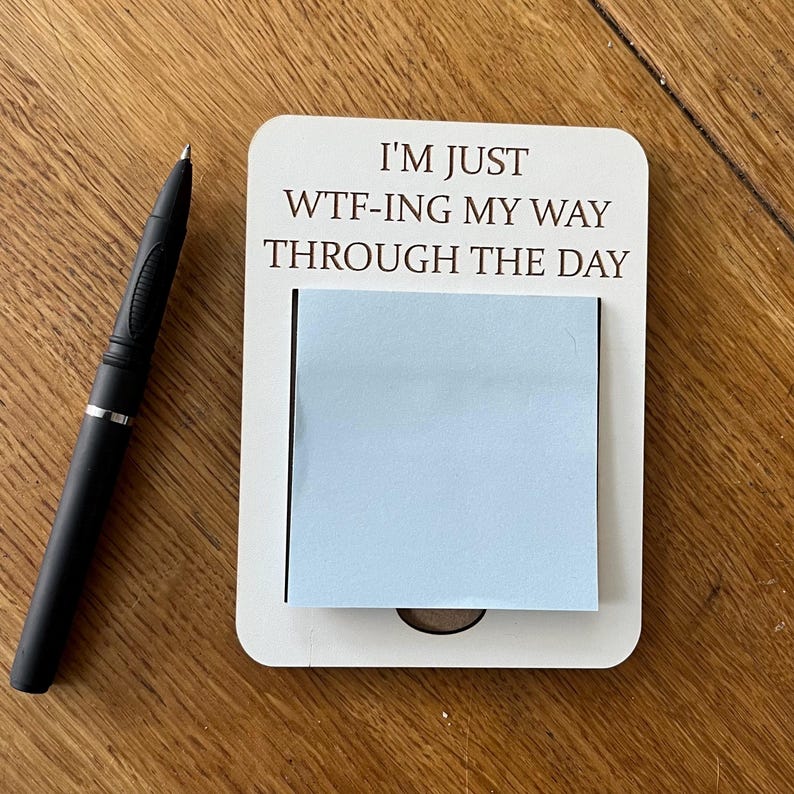 K&ouml;nnte beinhalten: Ein wei&szlig;es Holz-Notizbrett mit dem Text "I'm just WTF-ing my way through the day". Ein hellblauer Haftnotiz ist an dem Brett befestigt.