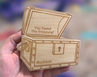 Puede incluir: Un cofre del tesoro de madera con una tapa con bisagras, grabado con las palabras "You found the treasure!" y el nombre "Madison".