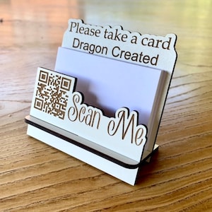 May include: White wooden business card holder with a white card, a QR code, and the text "Please take a card Dragon Created Scan Me".