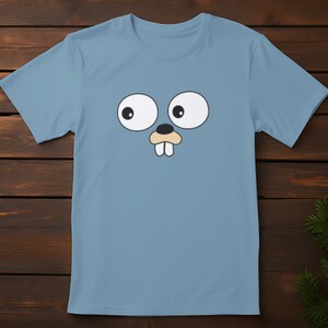May include: A light blue t-shirt with a cartoon face of a gopher with large eyes and two teeth. The gopher is wearing a brown nose.