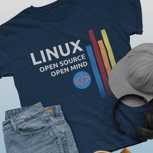 May include: A navy blue t-shirt with the text "LINUX OPEN SOURCE OPEN MIND" and a blue circle with white angle brackets. The shirt has a vintage look with colorful vertical stripes on the right side.