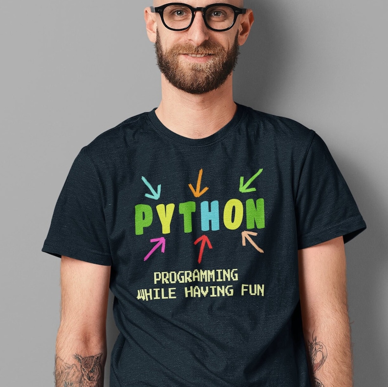 May include: A dark blue t-shirt with the word "PYTHON" in colorful letters surrounded by colorful arrows. The text "PROGRAMMING WHILE HAVING FUN" is printed below the word "PYTHON" in a pixelated font.