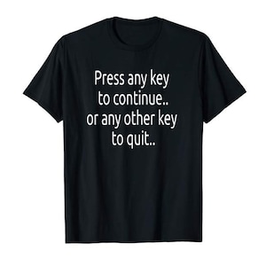 Puede incluir: Camiseta negra con texto blanco: "Press any key to continue.. or any other key to quit..". La camiseta tiene cuello redondo y mangas cortas. El texto está centrado en la parte delantera.