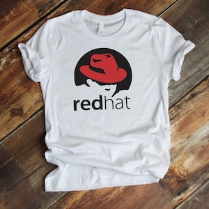May include: White t-shirt featuring a red hat logo and the text "redhat" printed on the front.