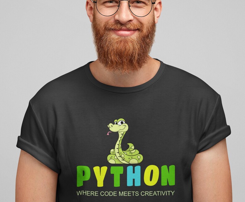 Puede incluir: Camiseta negra con una serpiente de dibujos animados y la palabra "PYTHON" en verde, amarillo y azul. El texto "WHERE CODE MEETS CREATIVITY" est&aacute; debajo de la palabra "PYTHON". La serpiente es verde con manchas amarillas y una lengua rosa.