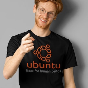 Peut inclure: Un t-shirt noir avec un logo Ubuntu orange et le texte "linux for human beings".