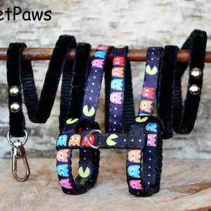 May include: Black ferret harness with a Pac-Man design and matching leash. The harness has a black velvet leash with gold accents.