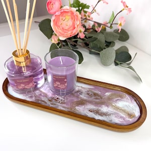 May include: A wooden tray with a purple and white resin design, holding a glass jar diffuser with reeds, a candle, and a floral arrangement. The diffuser and candle are purple. The tray is approximately 30 cm long.