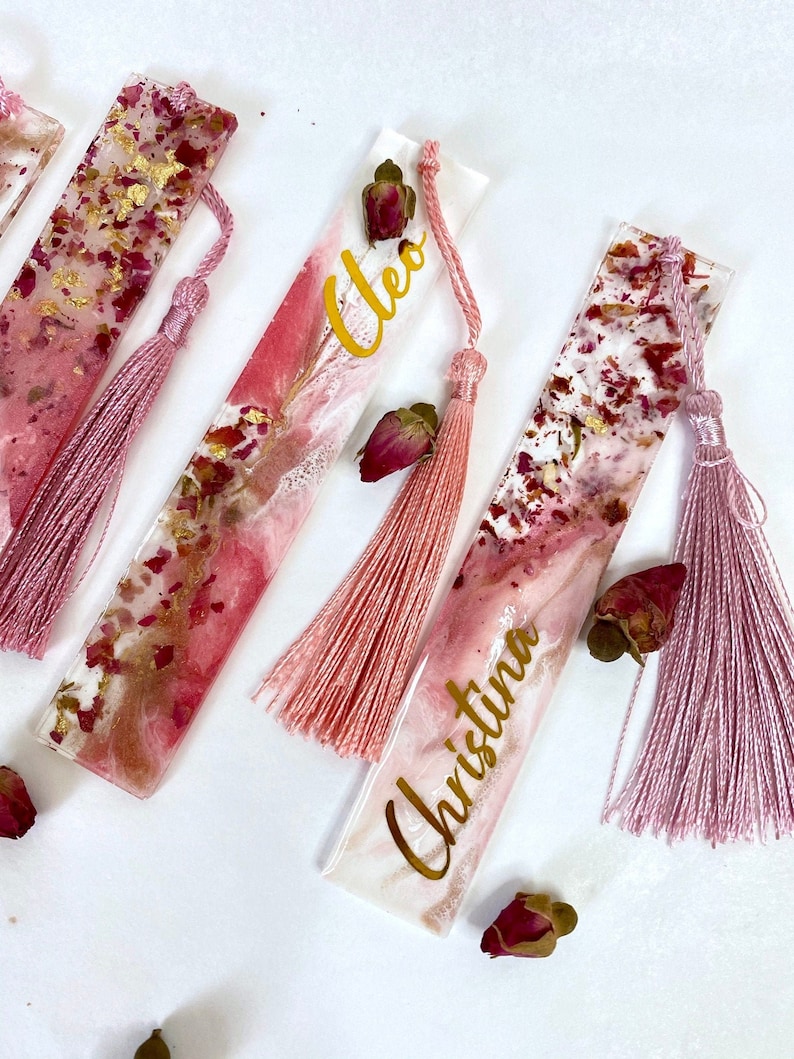 Close-up of white and pink resin bookmarks with dried roses and gold leaf, showing handmade details and variations including personalised and non-personalised options, elegant bookmarks for readers or gifts