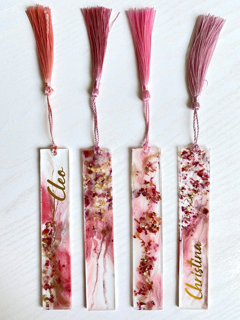 Set of four resin bookmarks featuring a white and pink design with real dried roses and shimmering gold leaf, finished with clear resin at the top. A charming boho-style accessory, perfect for gifts, book lovers, and book club favors.