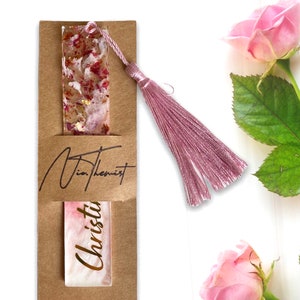 White and pink resin bookmark with dried roses and gold leaf, personalised with gold vinyl, inside a single packaging sleeve with logo, handmade bookmark for readers or gifts.