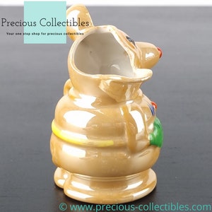 Peut inclure: Un petit pichet en c&eacute;ramique brun en forme de souris de dessin anim&eacute;. Le pichet a une bande jaune autour du milieu et des d&eacute;tails verts et rouges sur le c&ocirc;t&eacute;. Le pichet est verni et a une finition brillante.