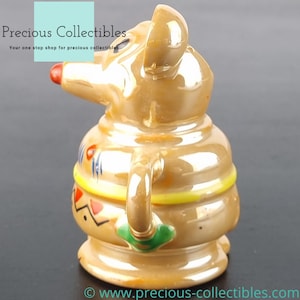 Peut inclure: Une figurine en c&eacute;ramique d'une souris brune avec un motif jaune, rouge et bleu. La souris tient une tasse verte dans sa main.