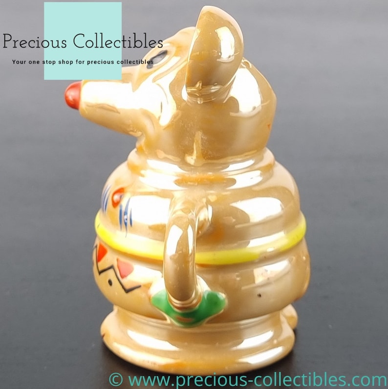 Peut inclure: Une figurine en c&eacute;ramique d'une souris brune avec un motif jaune, rouge et bleu. La souris tient une tasse verte dans sa main.