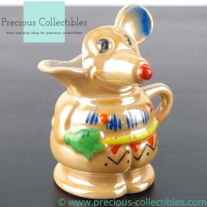 Peut inclure: Une cr&eacute;mier en c&eacute;ramique en forme de souris. La souris porte une tenue color&eacute;e avec des accents verts, jaunes, rouges et bleus. La cr&eacute;mier a un gla&ccedil;age brillant et iridescent.