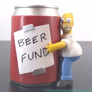 May include: A red and silver can-shaped money box with the words "BEER FUND" on a white note. A yellow cartoon character is hugging the money box. The character is wearing a white shirt, blue trousers, and grey shoes.