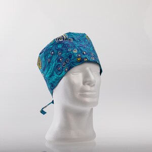 May include: A blue and green patterned surgical scrub cap with a tie string. The cap has a swirling pattern with yellow accents.