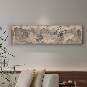 May include: A long, horizontal painting of a traditional Chinese landscape scene with mountains, trees, and a river. The painting is framed in a dark wood frame and hangs on a light gray wall above a white sofa.