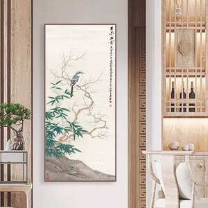 May include: A vertical painting of a bird perched on a branch with green leaves. The background is a light beige with Chinese calligraphy in black ink.