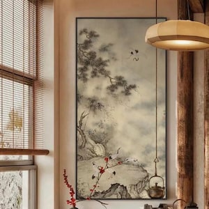 May include: A framed landscape painting in the Asian style, featuring a misty mountain scene with cranes and a waterfall. The artwork is predominantly in shades of gray, black, and beige, with red accents from a flowering branch in the foreground. A teapot hangs in the lower right.