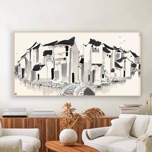 Könnte beinhalten: Ein Schwarzweiß-Tuschbild eines traditionellen chinesischen Dorfes mit Häusern und einer Brücke über einen Kanal. Das Bild ist gerahmt und hängt an einer weißen Wand in einem Wohnzimmer.