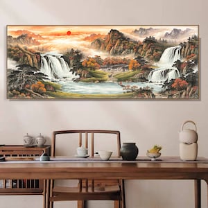 May include: A rectangular framed painting showcases a mountain landscape with waterfalls, a lake, and a sunset. The artwork uses orange, red, and green hues, creating a peaceful scene. The painting is displayed above a wooden table, adding to the room's decor.