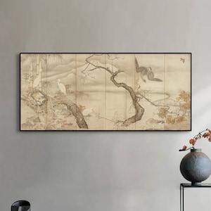Op de afbeelding: Een ingelijste print van een traditionele Japanse schildering die een boom met vogels en witte reigers afbeeldt. De schildering is in tinten bruin, wit en grijs en is geplaatst tegen een lichtgrijze muur.