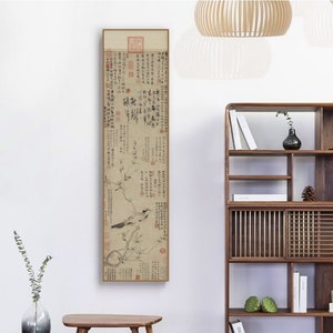 May include: A framed black and white print of a traditional Chinese painting featuring a bird perched on a branch with a background of calligraphy. The print is framed in a thin gold frame and is hanging on a white wall.