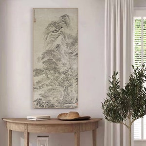 Op de afbeelding: Een zwart-witte inkttekening van een berglandschap met bomen en een waterval. De tekening is ingelijst en hangt aan een witte muur.