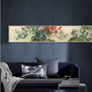 Op de afbeelding: Een lang, rechthoekig, ingelijst kunstwerk met een traditionele Aziatische schildering. Het kunstwerk toont kleurrijke bloemen, vogels en bladeren in tinten rood, wit en groen tegen een lichte achtergrond. De lijst is lichtgoudkleurig.