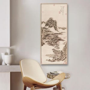 Könnte beinhalten: Ein Schwarzweiß-Tuschbild einer Berglandschaft mit einem Fluss, der durch sie fließt. Das Bild ist in einem hellen Holzrahmen gerahmt und hängt an einer weißen Wand.