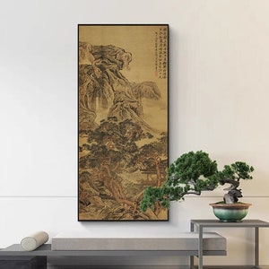 Può includere: Una stampa incorniciata in nero di un dipinto tradizionale cinese di paesaggio che rappresenta montagne, alberi e una cascata. Il dipinto è appeso a una parete bianca sopra un divano grigio e un tavolino con un bonsai.